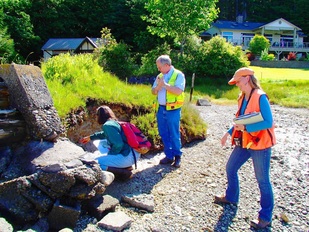 People in bright orange and yellow safety vests assessing erosion by a pile of rocks