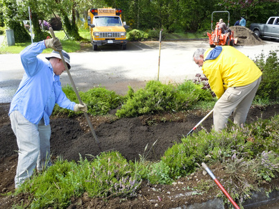 Two volunteers digging a space for a rain garden